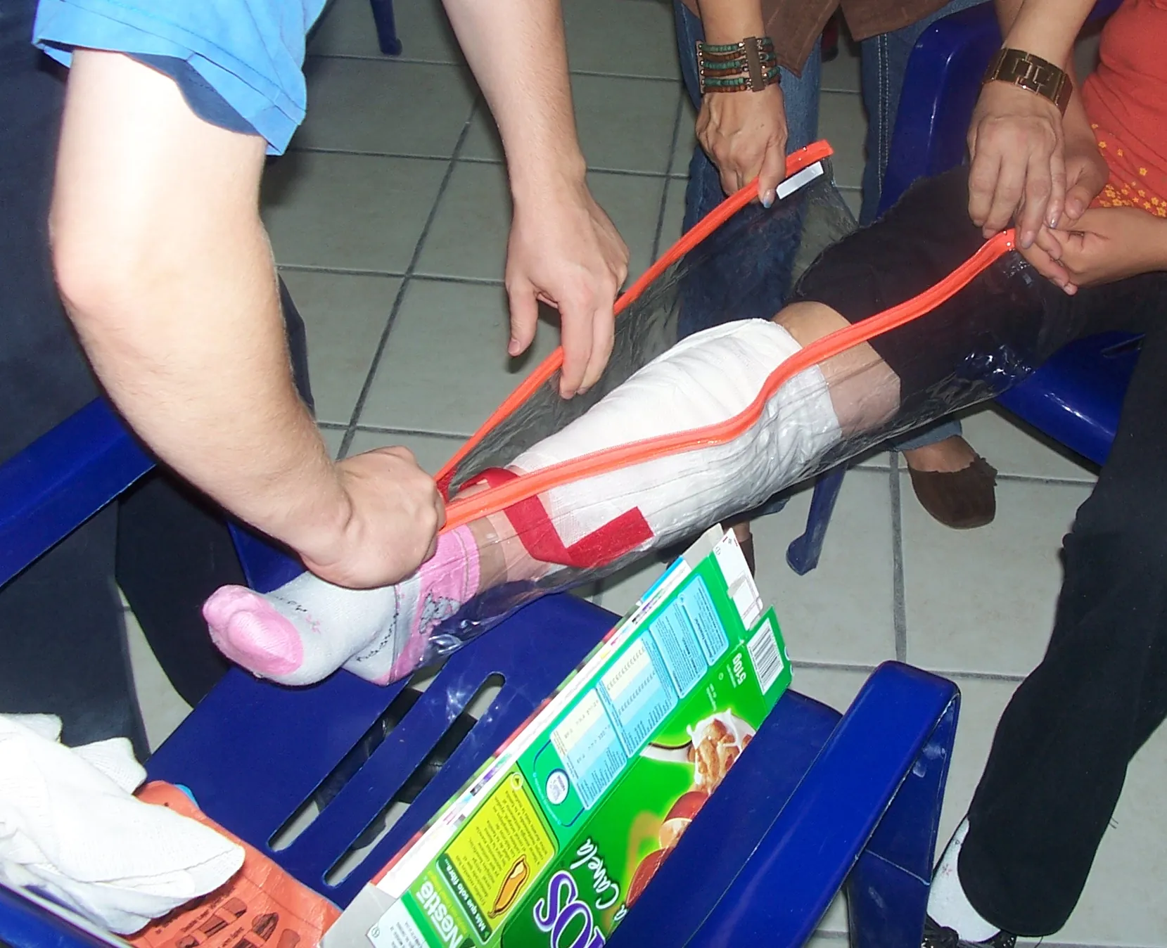 Inmovilización de una pierna con una férula improvisada y vendas, en una práctica de primeros auxilios.