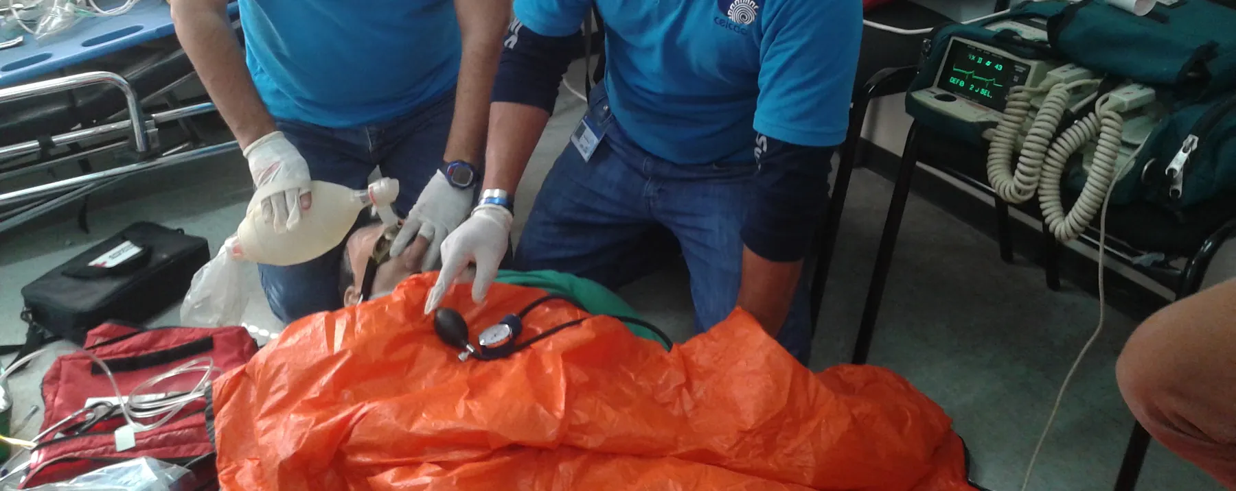 Inmovilización en colchón de vacío naranja: manos con guantes ajustan el colchón y toman signos vitales.