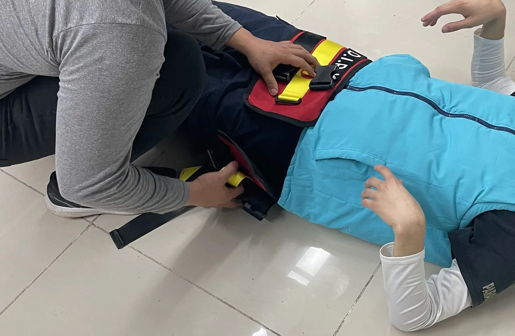 Colocación de una férula pélvica a un compañero acostado en el piso del aula.