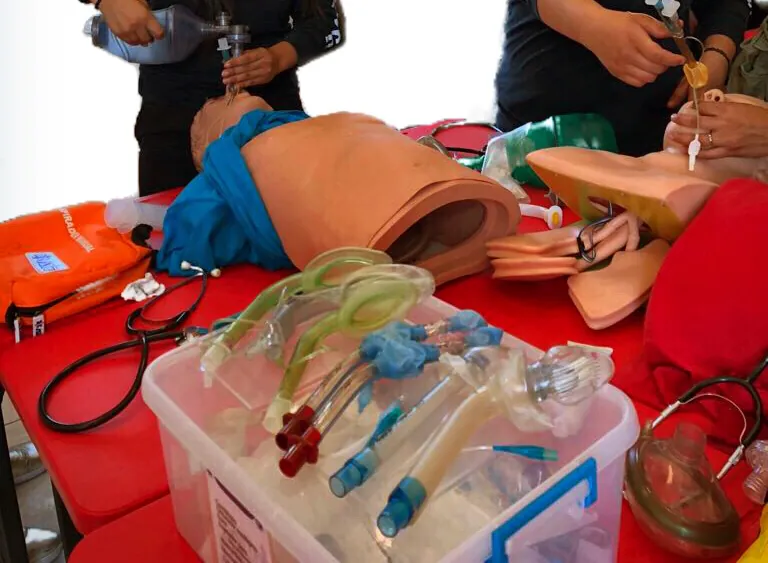 Equipo de vía aérea y oxigenoterapia sobre una mesa roja: dispositivos supraglóticos, tubos, mascarillas y maniquíes.