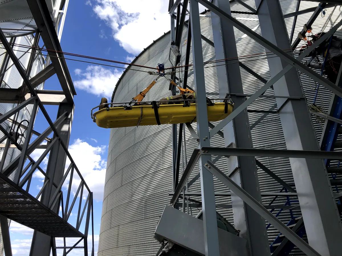 Camilla amarilla izada entre silos y una estructura metálica, con el cielo azul de fondo.