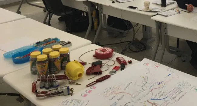 Candados, pinzas de bloqueo, tarjetas y un mapa mental sobre la mesa de un curso de bloqueo de energías.