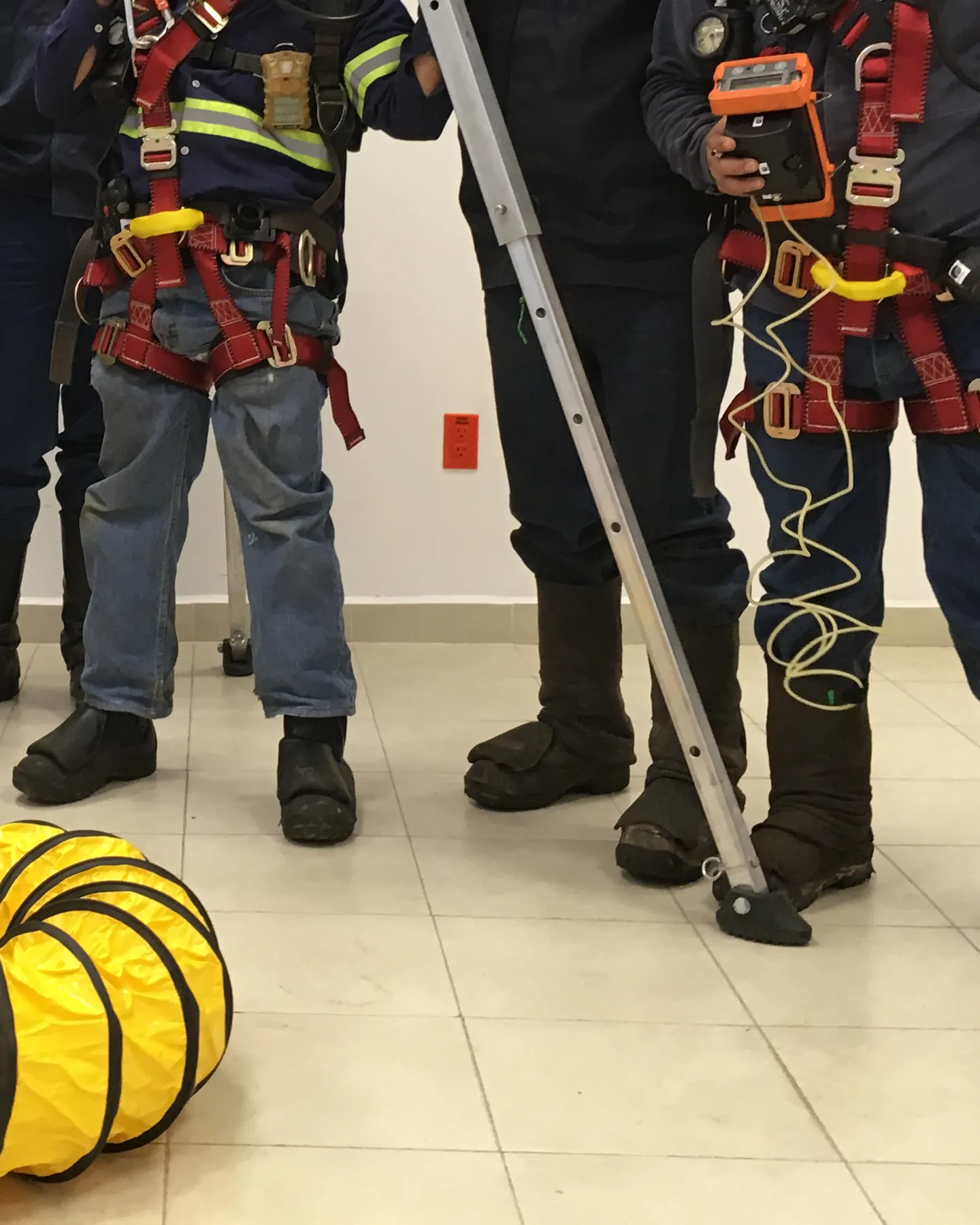 Participantes con arnés y detector de gases junto al trípode de un espacio confinado.